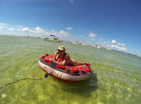 Big titted amateur lounges on an air mattress while naked in a ball cap