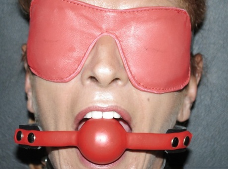 Mature submissive woman Lady Sarah poses in variety of restraining devices